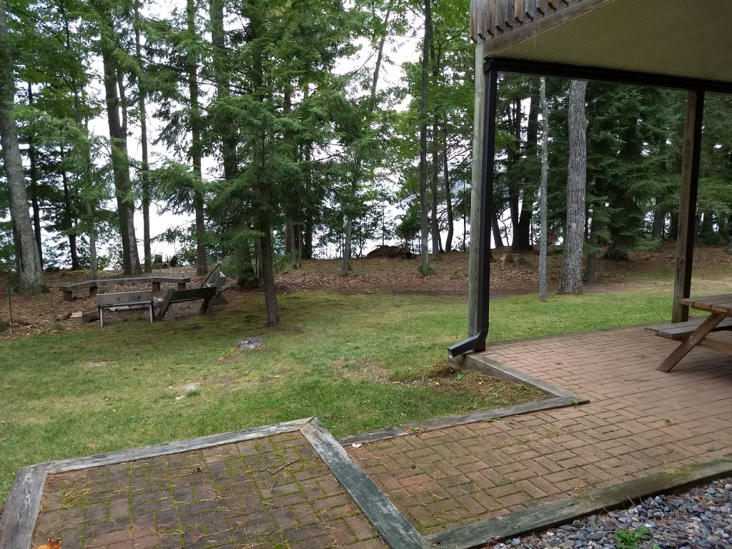 patio, grasss, fire ring overlooking trees and water
